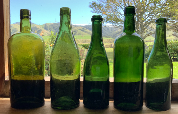Five antique green glass bottles